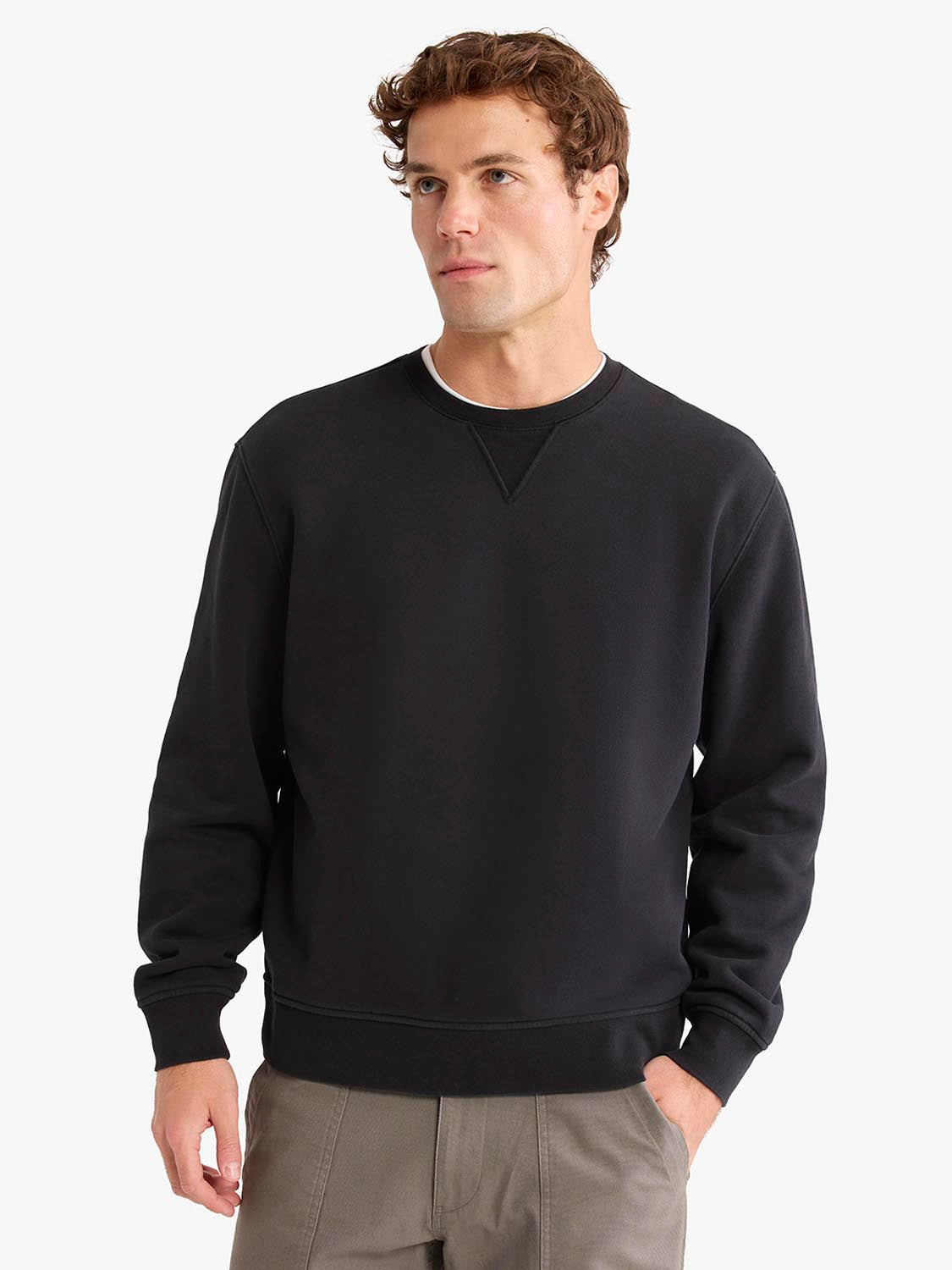 Man wearing a black crewneck sweatshirt with ribbed cuffs and waistband.