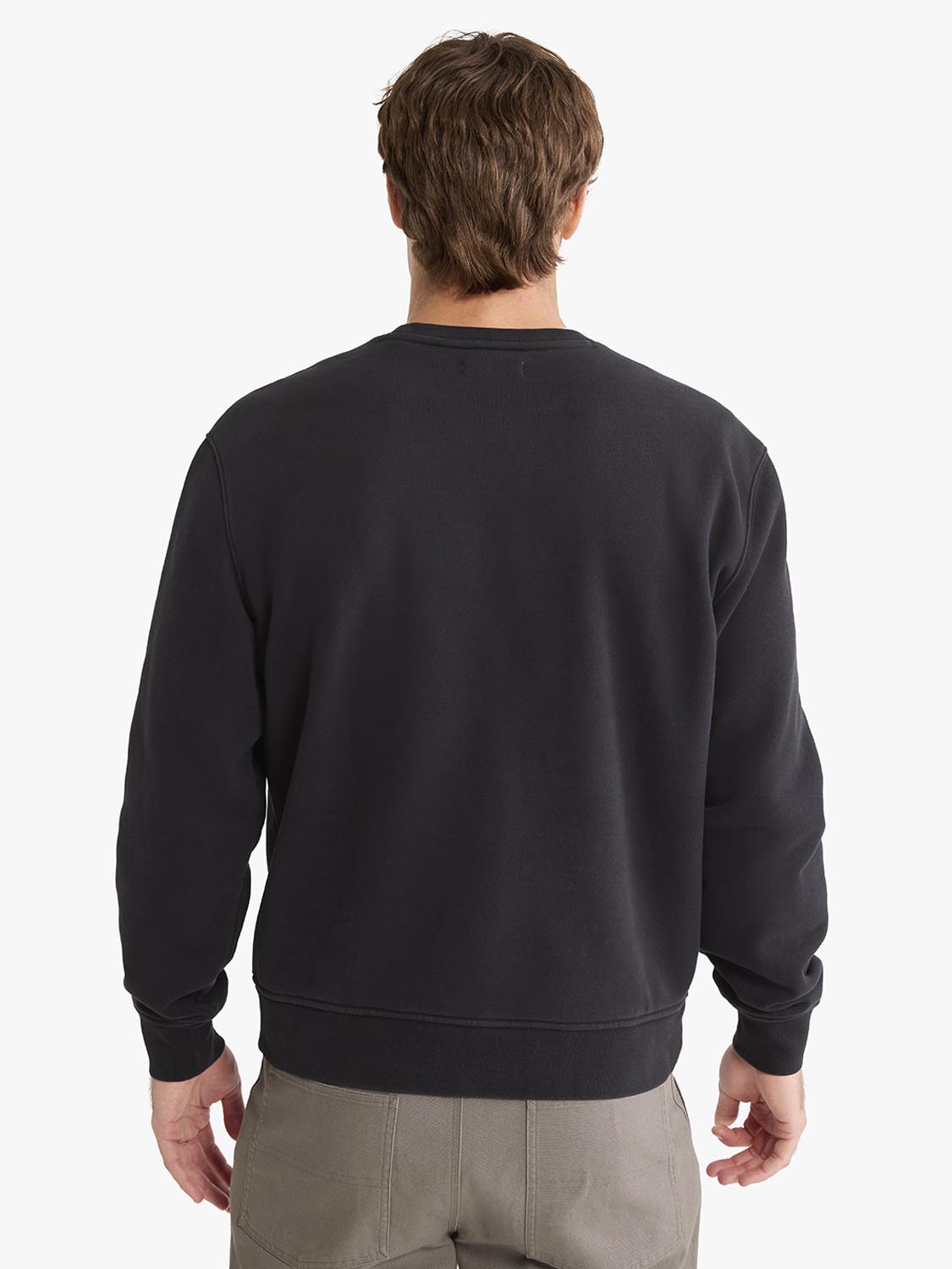 Man wearing black crewneck sweatshirt with long sleeves, shown from back view.
