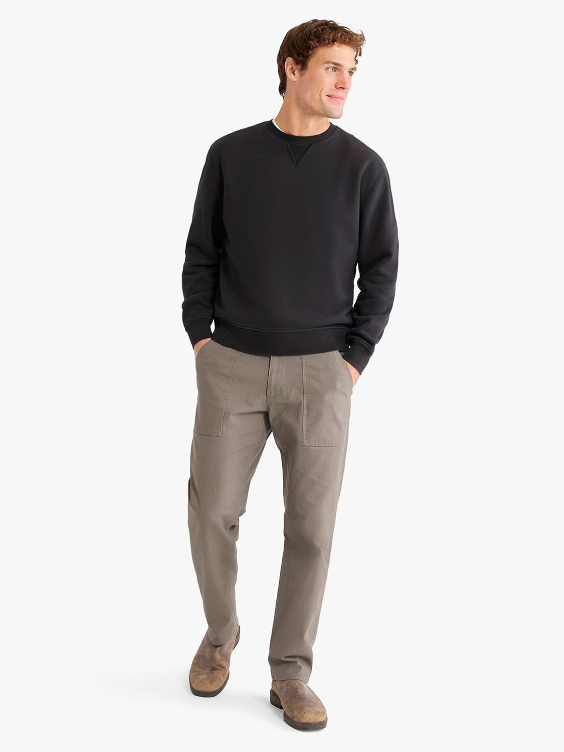 Man wearing a black crewneck sweatshirt with tan utility pants and suede boots.