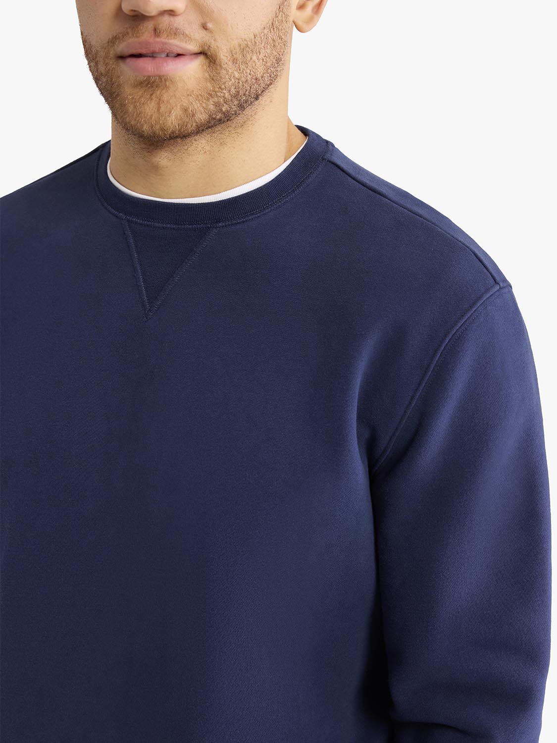 Man wearing a navy crewneck sweatshirt with white trim around the collar.