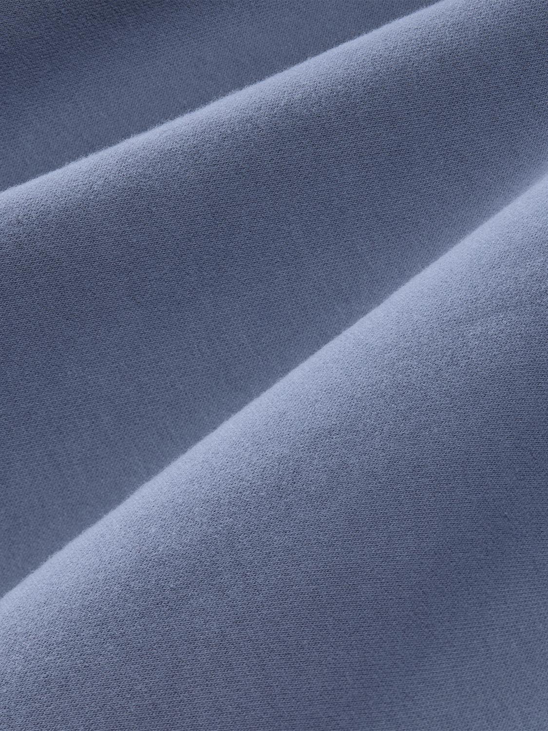 Close-up view of soft blue crewneck fabric with visible texture and natural folds throughout.