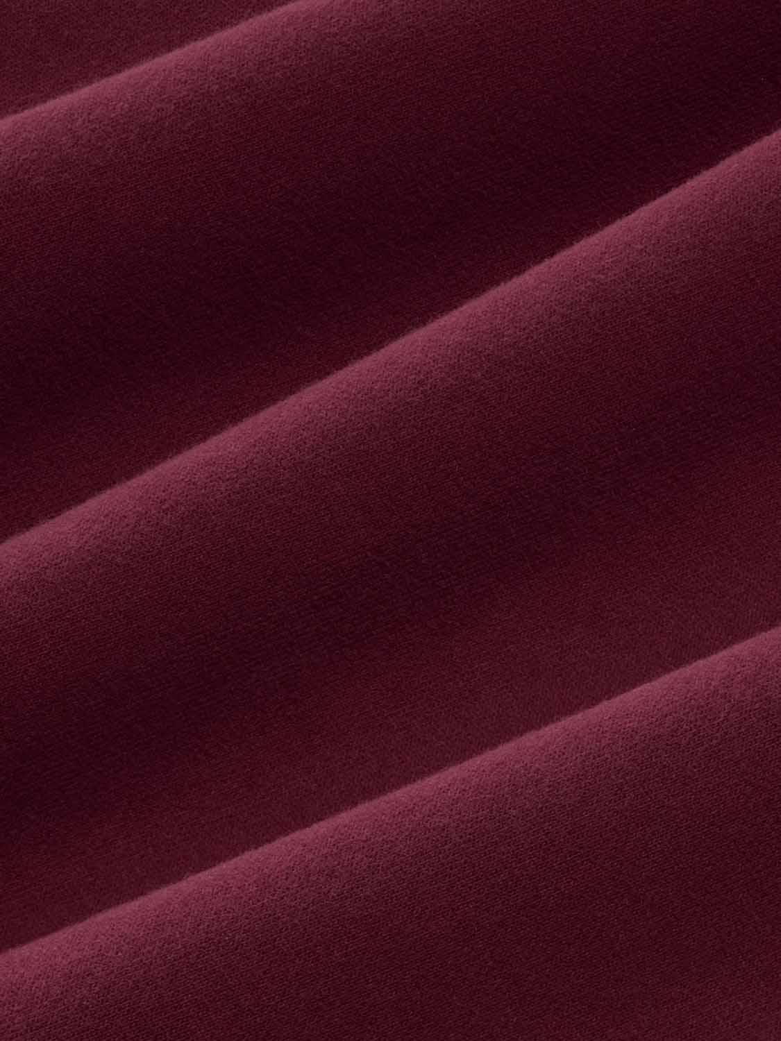 Burgundy crewneck sweatshirt with textured fabric and diagonal seam details visible.
