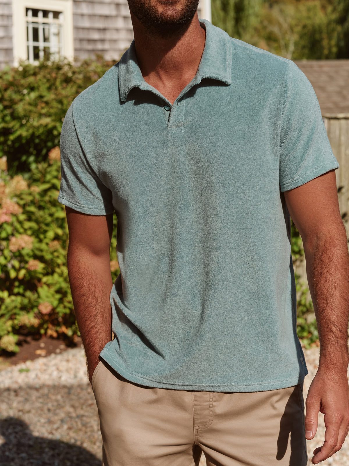 Man wearing a light blue terry polo shirt with a collar and short sleeves outdoors.