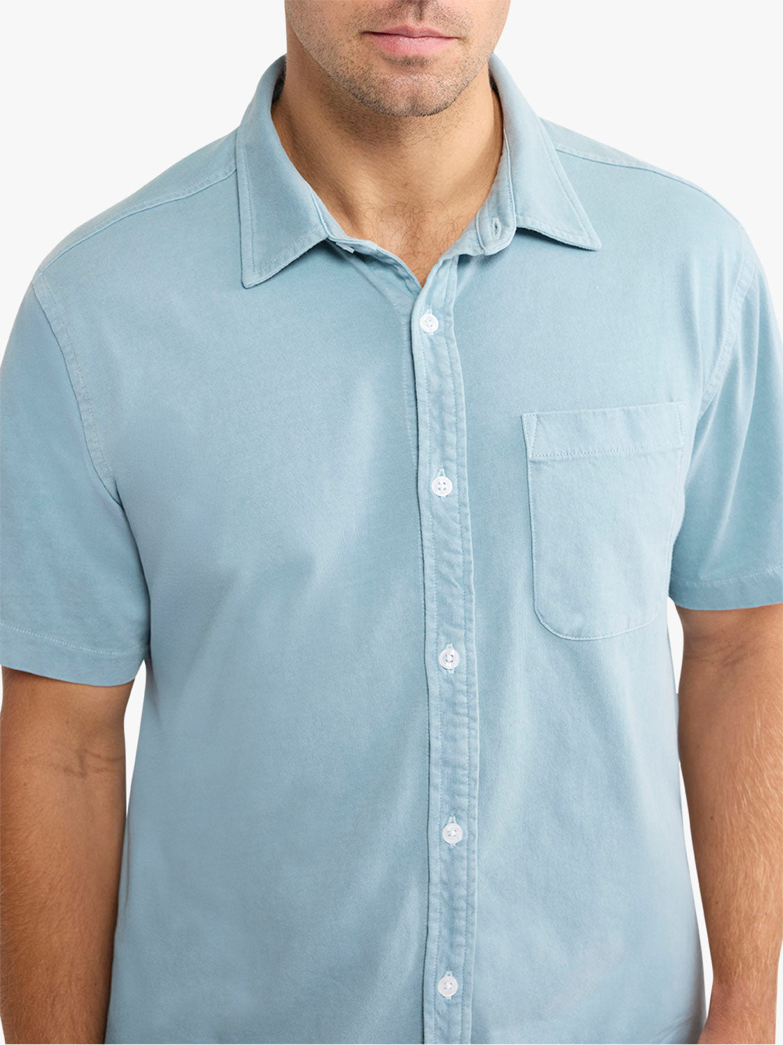 Man wearing a light blue short-sleeved button-front shirt with a chest pocket and collar.