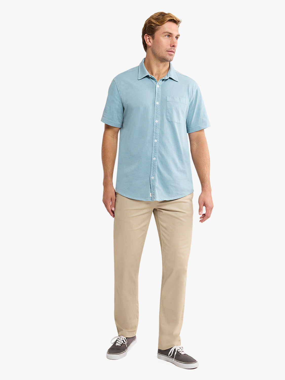 Man wearing a bay blue short-sleeve button-up shirt with a chest pocket and beige pants.