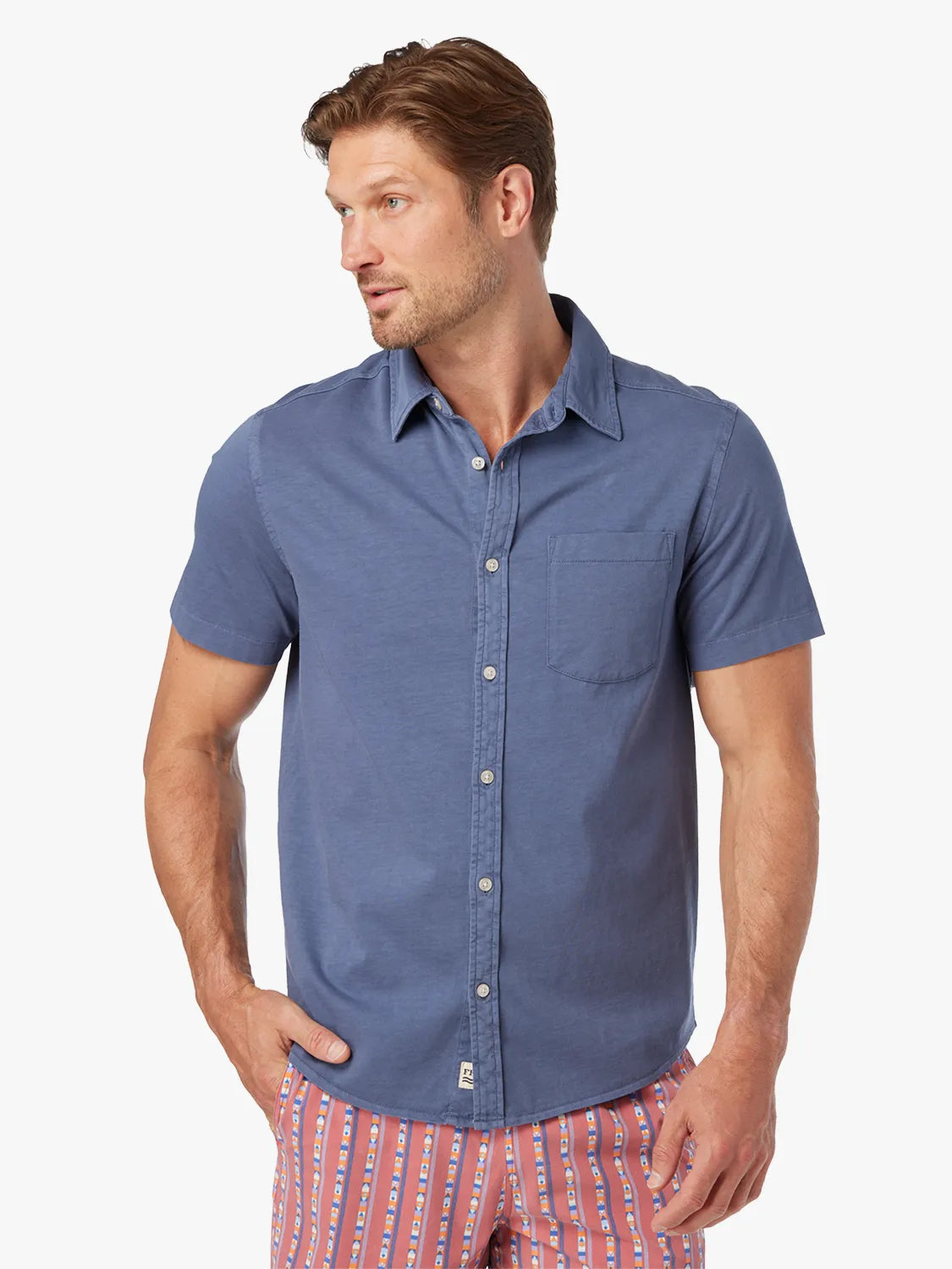 Man wearing a navy short-sleeve button-up shirt with a chest pocket and white buttons.