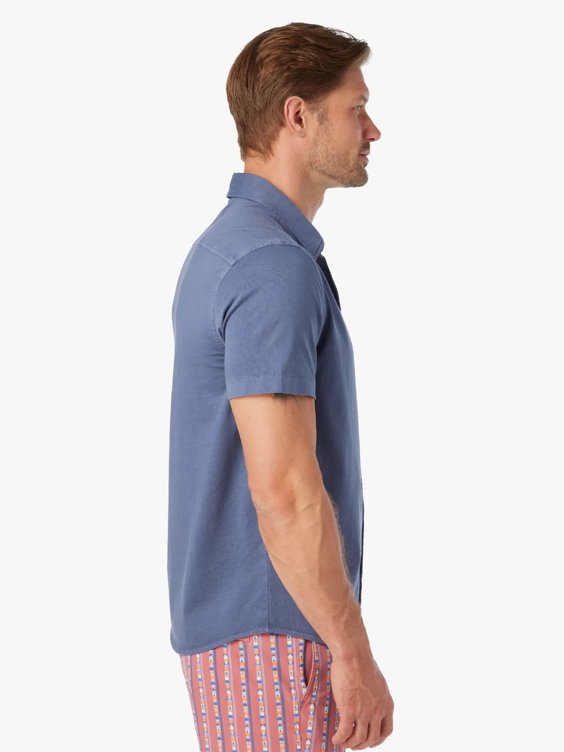 Man wearing a navy short-sleeved button-up shirt displayed in profile view.