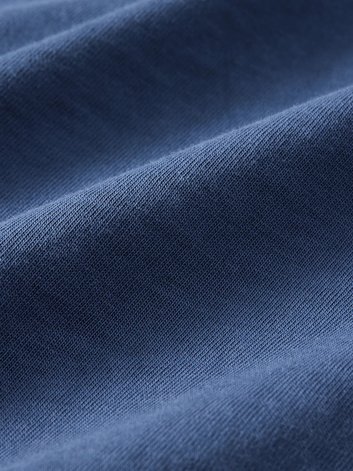 Close-up of navy blue woven fabric with visible textile weave and soft folds throughout.