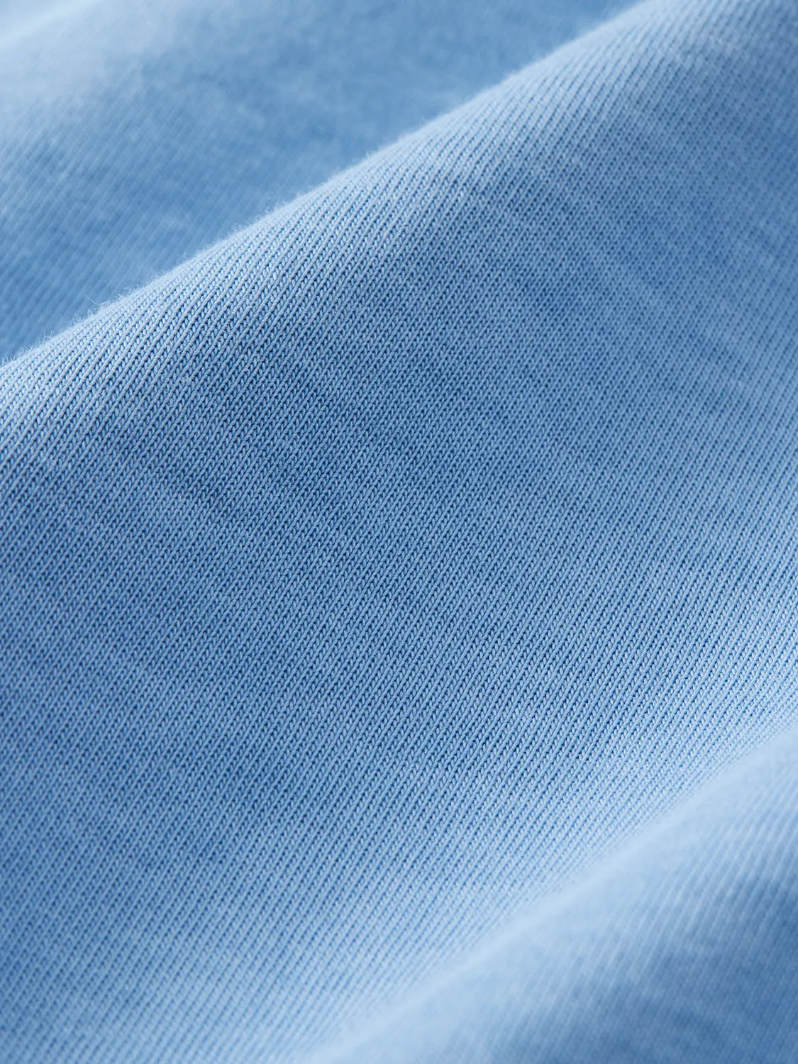 Light blue ribbed fabric with fine texture and diagonal folds throughout the material.