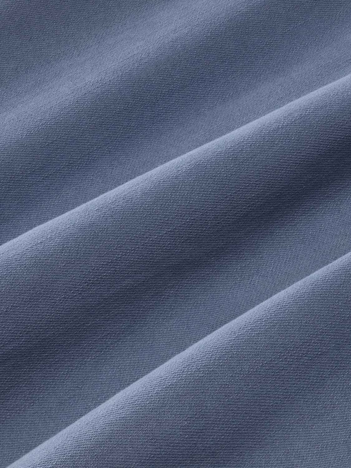Slate blue woven fabric with a textured surface and diagonal fold lines creating shadow variations.
