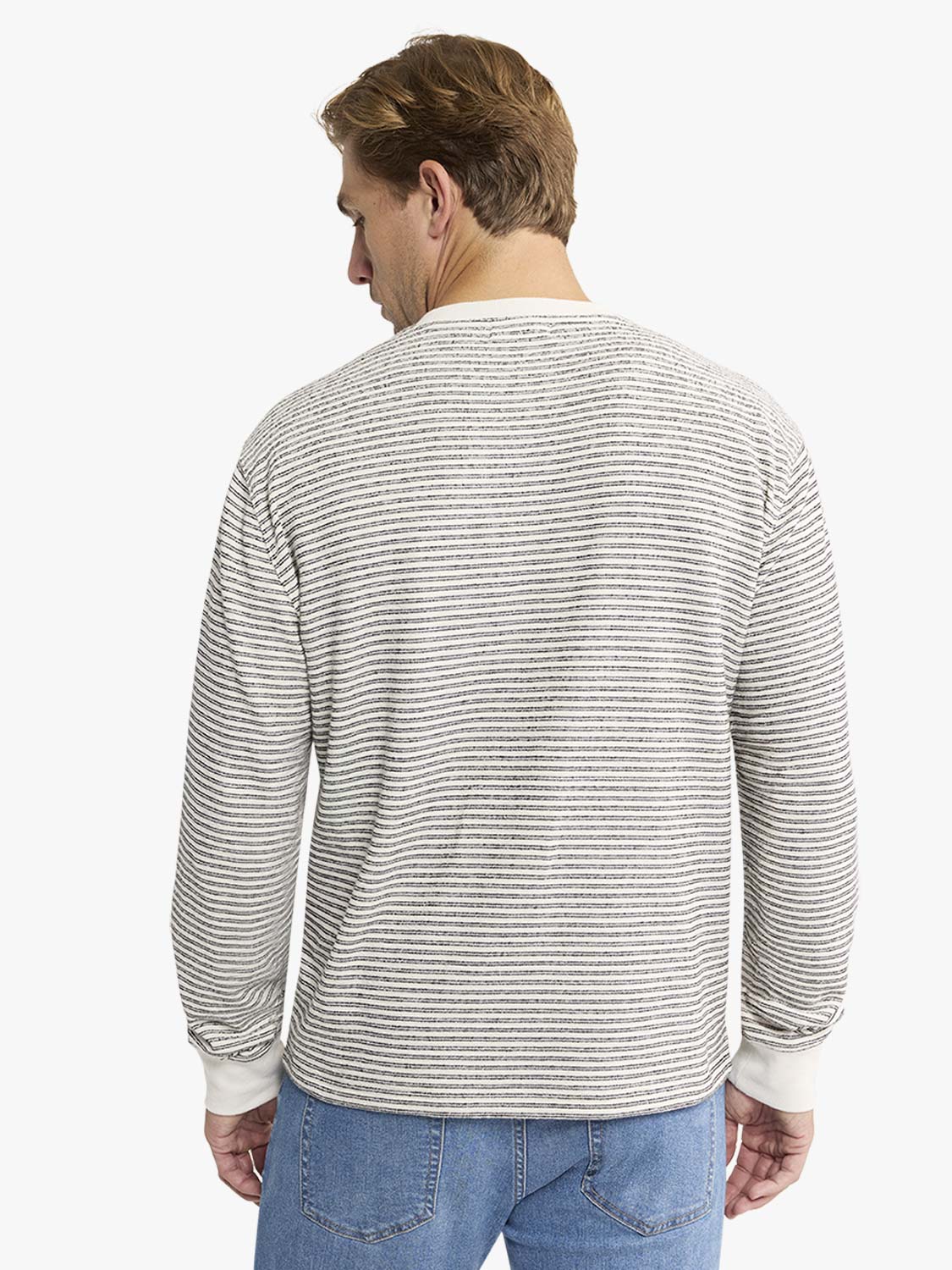 Man wearing a cream and gray striped terry crewneck sweatshirt with white ribbed cuffs and collar.