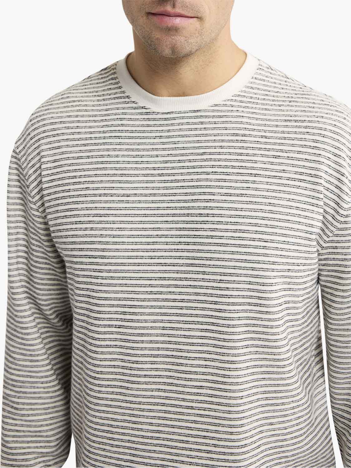 Man wearing a cream and navy striped long-sleeve crewneck terry sweatshirt with horizontal stripes throughout.