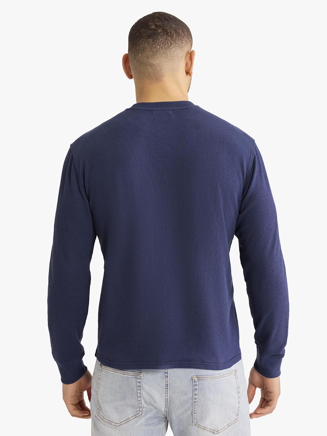 Man wearing a solid navy crewneck sweatshirt with long sleeves, shown from the back view.