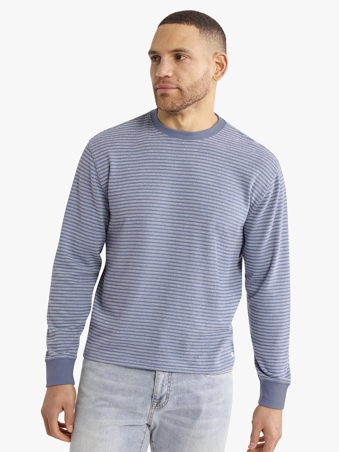 Man wearing a blue and white striped crewneck sweatshirt with long sleeves and ribbed cuffs.