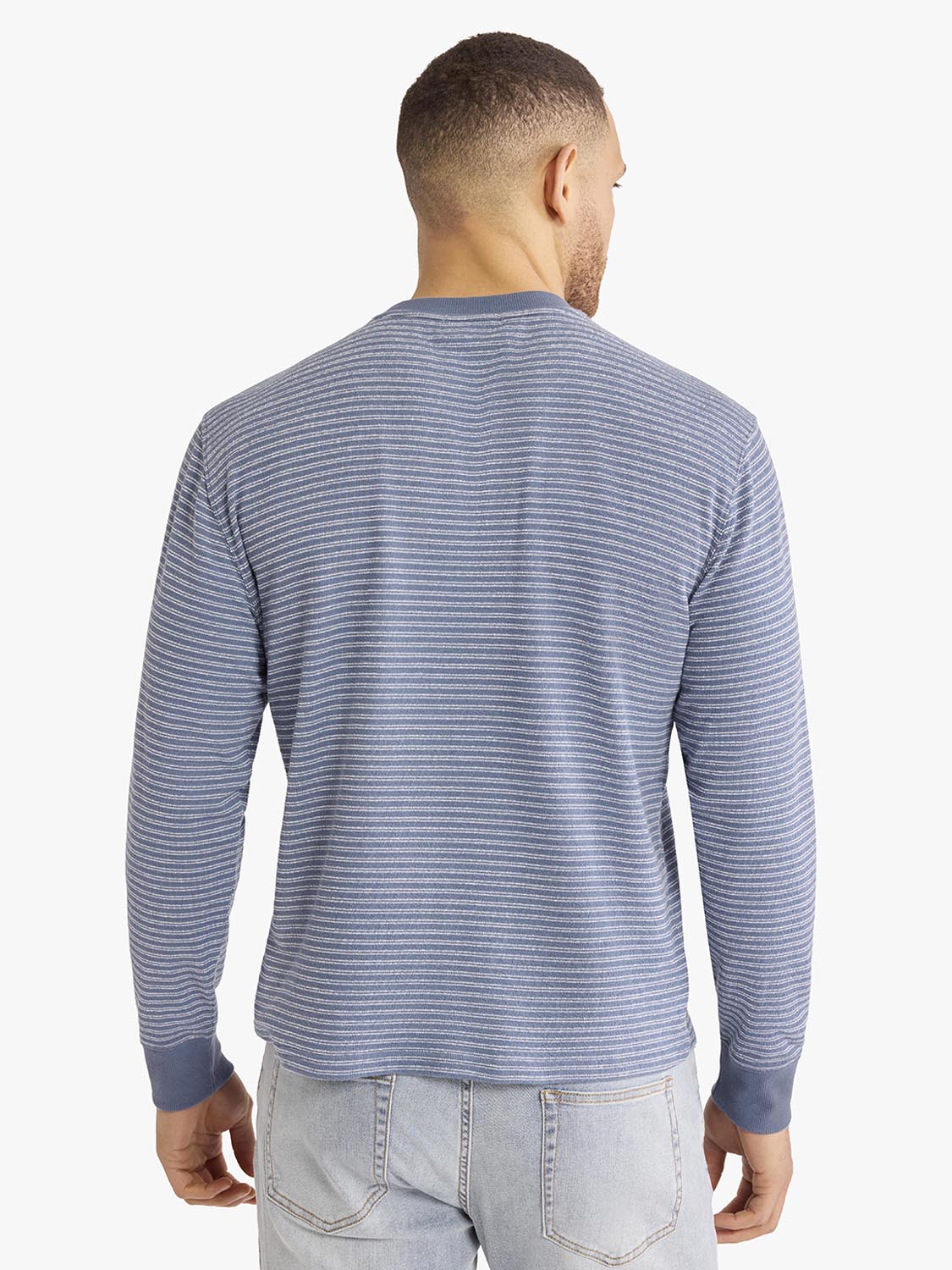 Man wearing blue and gray striped crewneck sweatshirt viewed from the back.