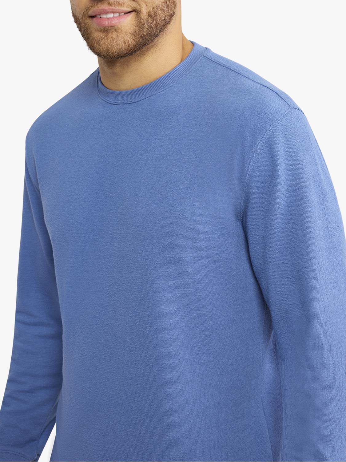 Man wearing a sea blue terry crewneck sweatshirt with long sleeves and ribbed neckline.