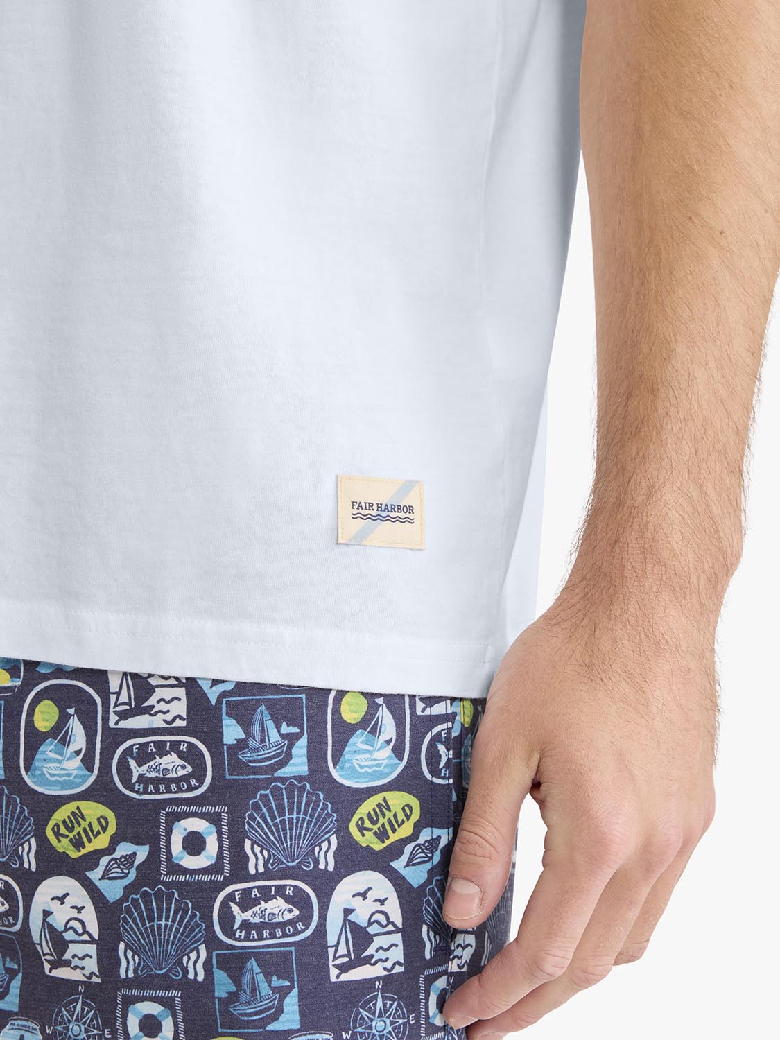 White short-sleeve t-shirt with Fair Harbor label and nautical-patterned swim shorts visible.