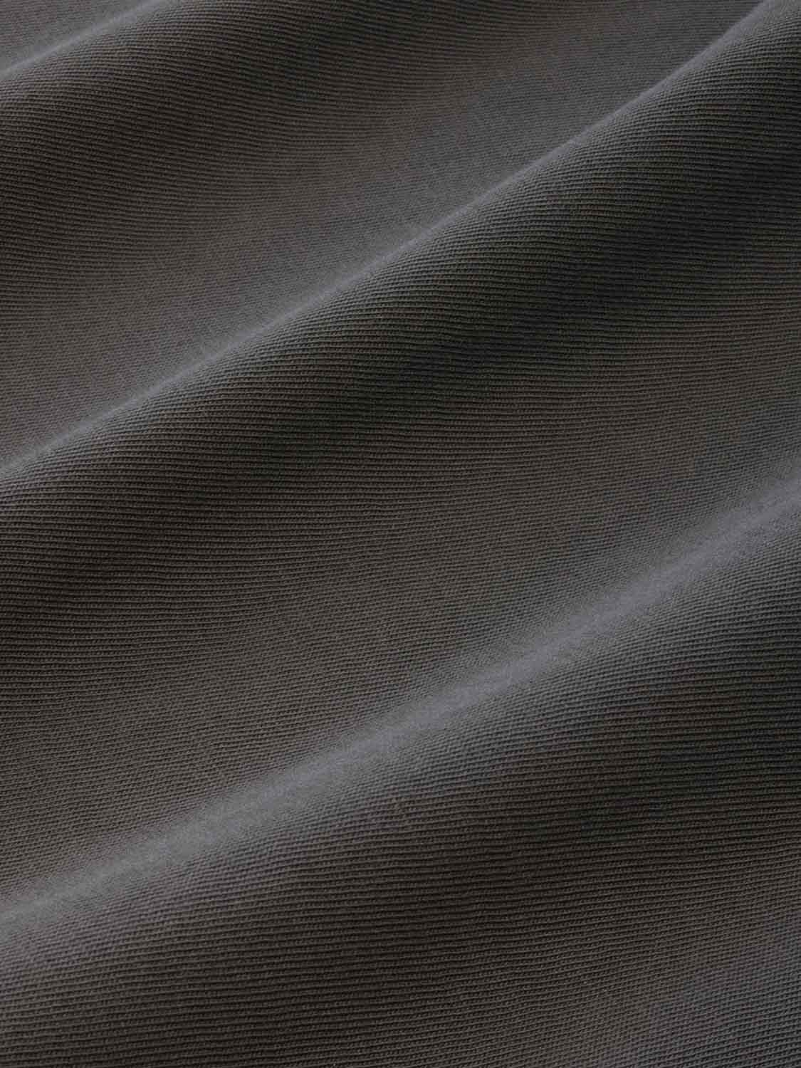 Close-up of charcoal gray ribbed fabric texture showing diagonal folds and draped material.
