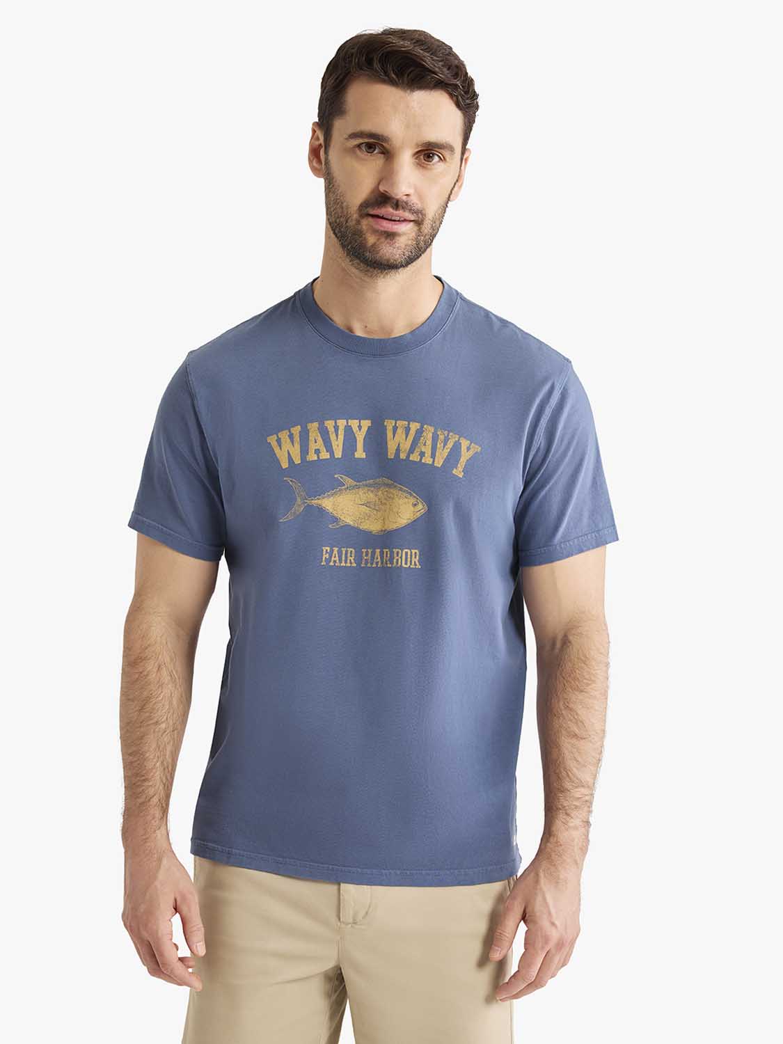 Man wearing a navy blue graphic tee with gold wavy wavy text and fish illustration.