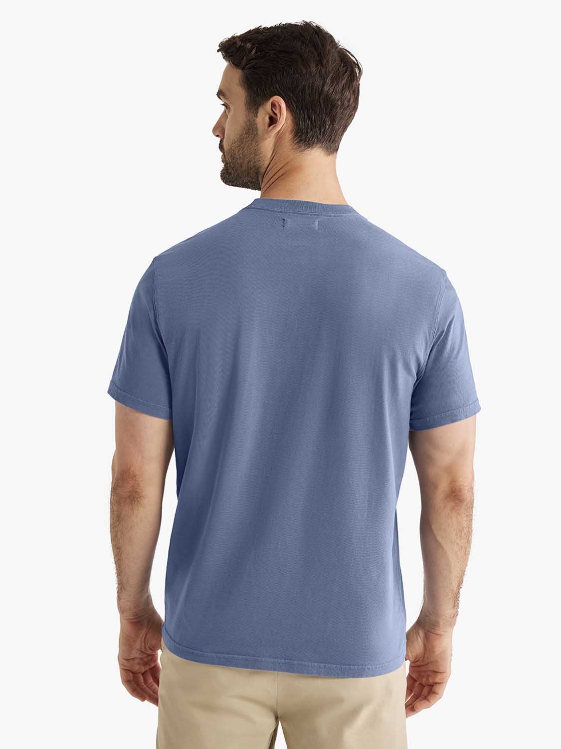 Man wearing a navy blue short-sleeve graphic t-shirt paired with beige pants, shown from the back.