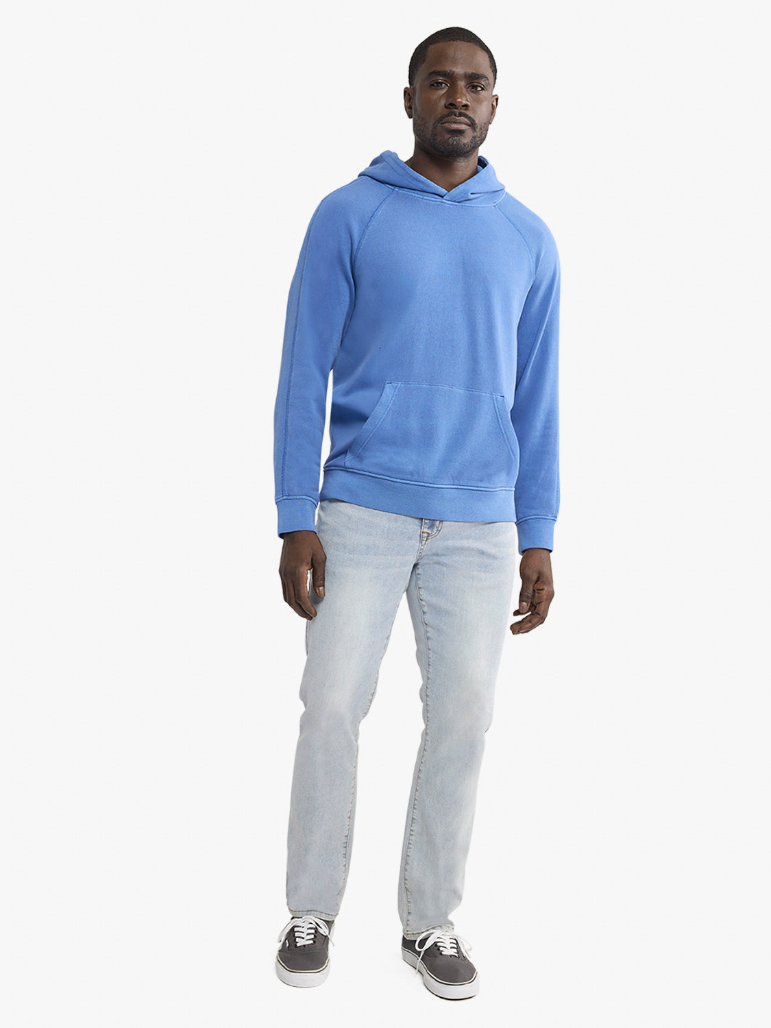 Man wearing a blue hoodie and light gray pants on a white background