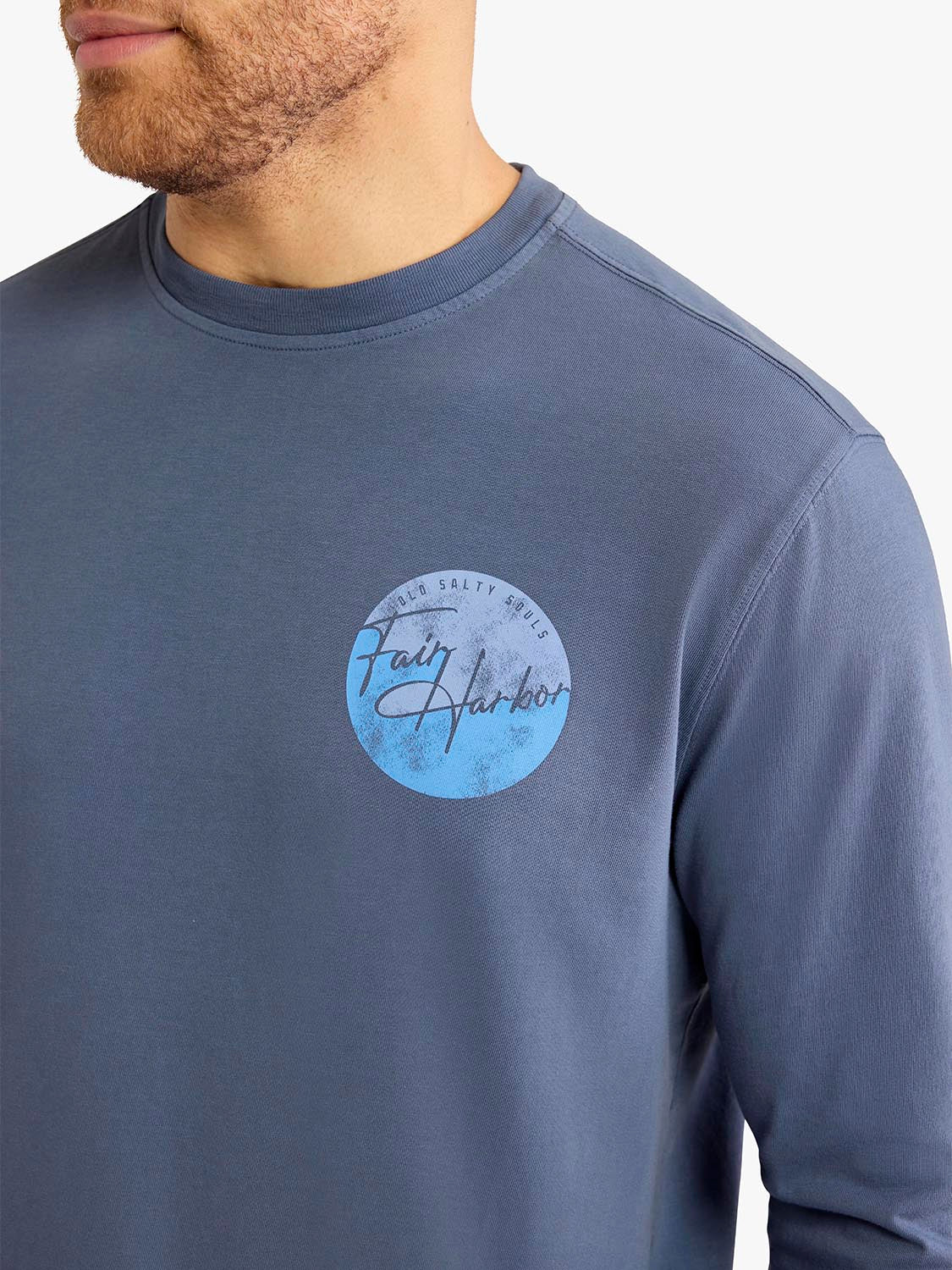 Man wearing a slate blue long sleeve tee with a circular graphic design on the chest.