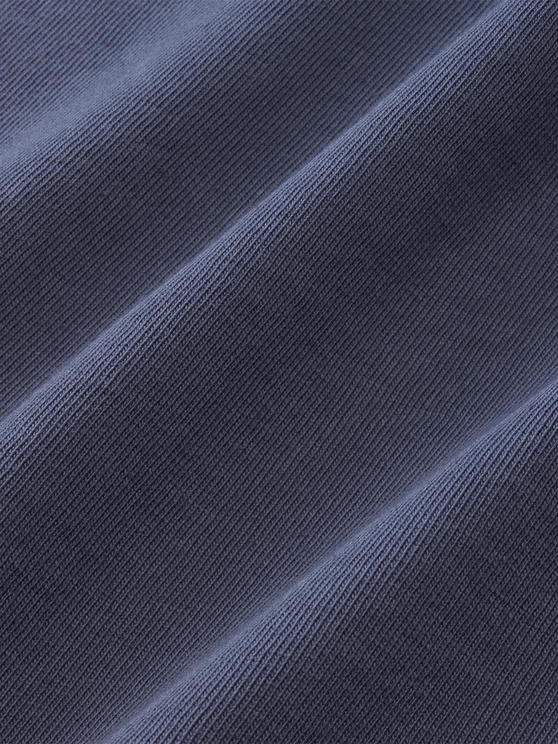 Blue long sleeve shirt fabric with a textured ribbed knit pattern and diagonal fold lines visible.