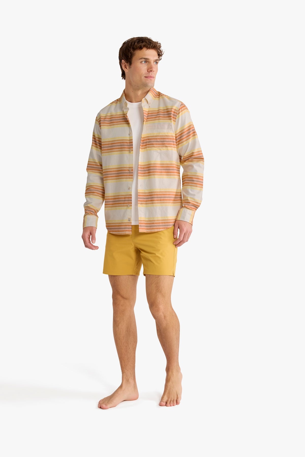 Man wearing a striped oxford shirt with orange and yellow horizontal stripes over a white undershirt.