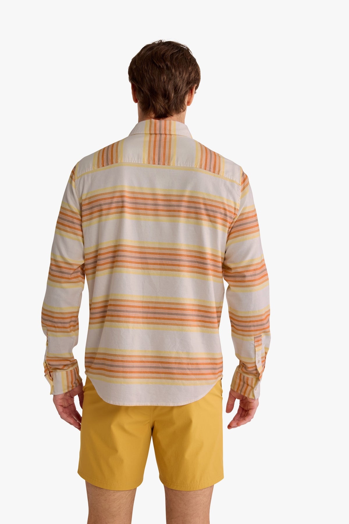 Man wearing a striped Oxford shirt with orange and yellow horizontal stripes over yellow shorts.