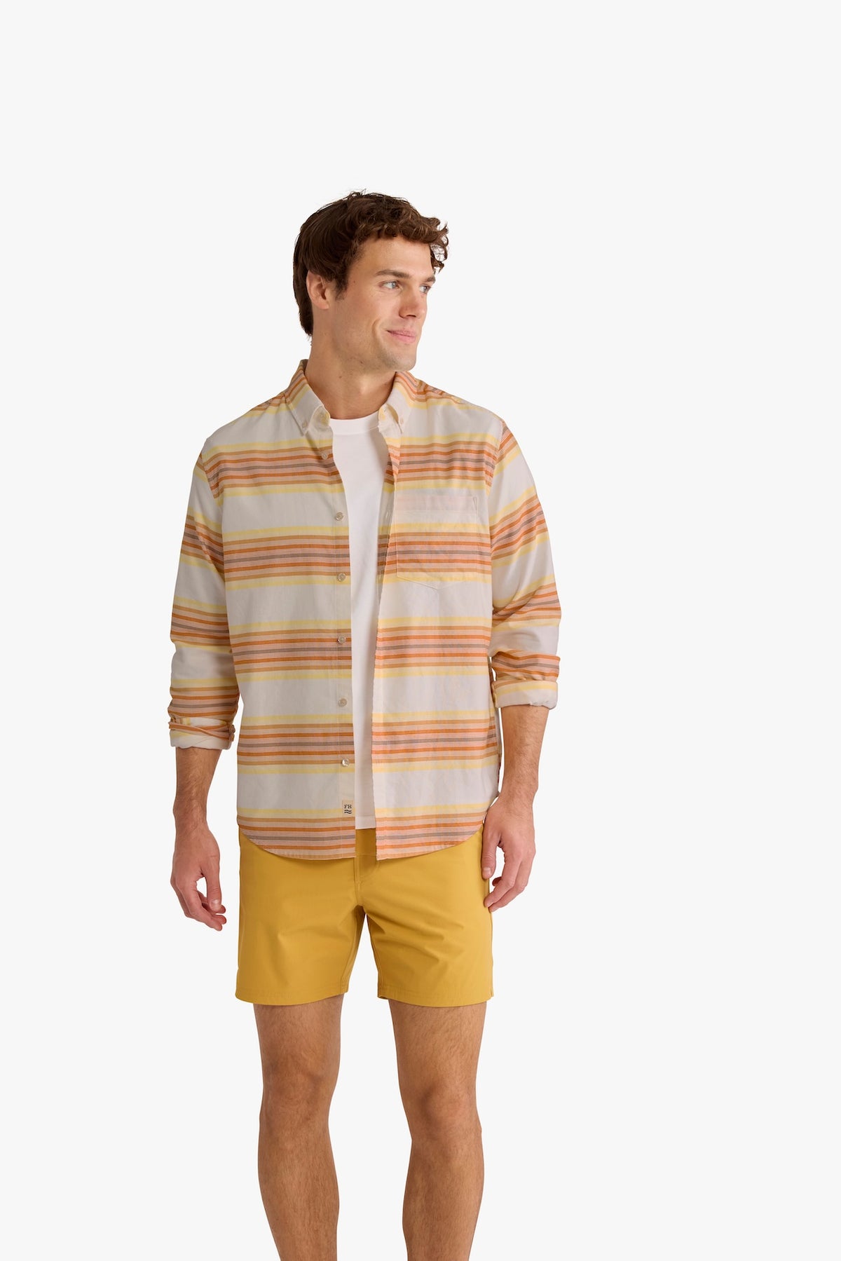 Man wearing a button-up oxford shirt with horizontal orange, yellow, and cream stripes.