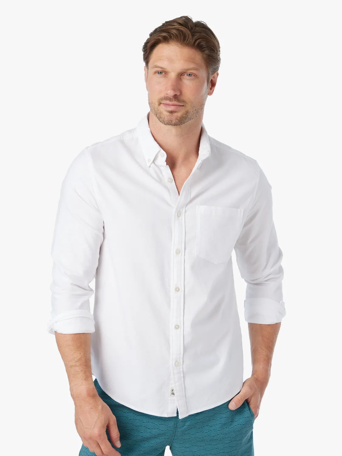Man wearing a white oxford button-up shirt with rolled sleeves and a chest pocket.