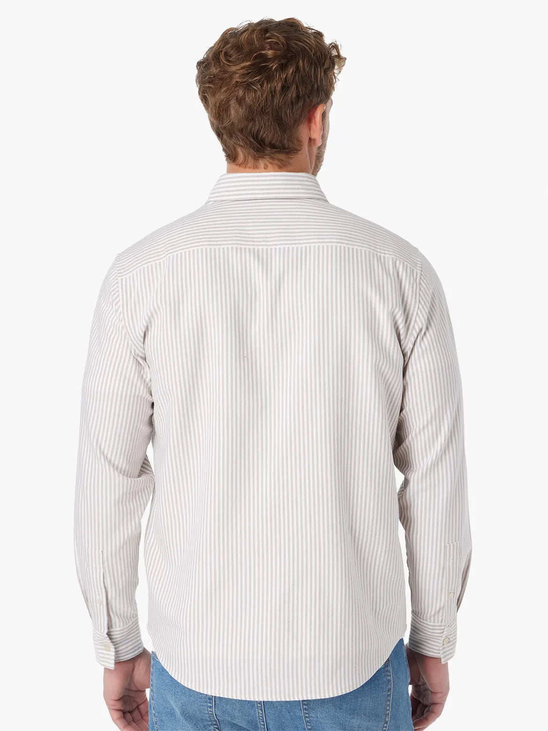 Man wearing a long-sleeved oxford shirt with vertical tan and white stripes, shown from behind.