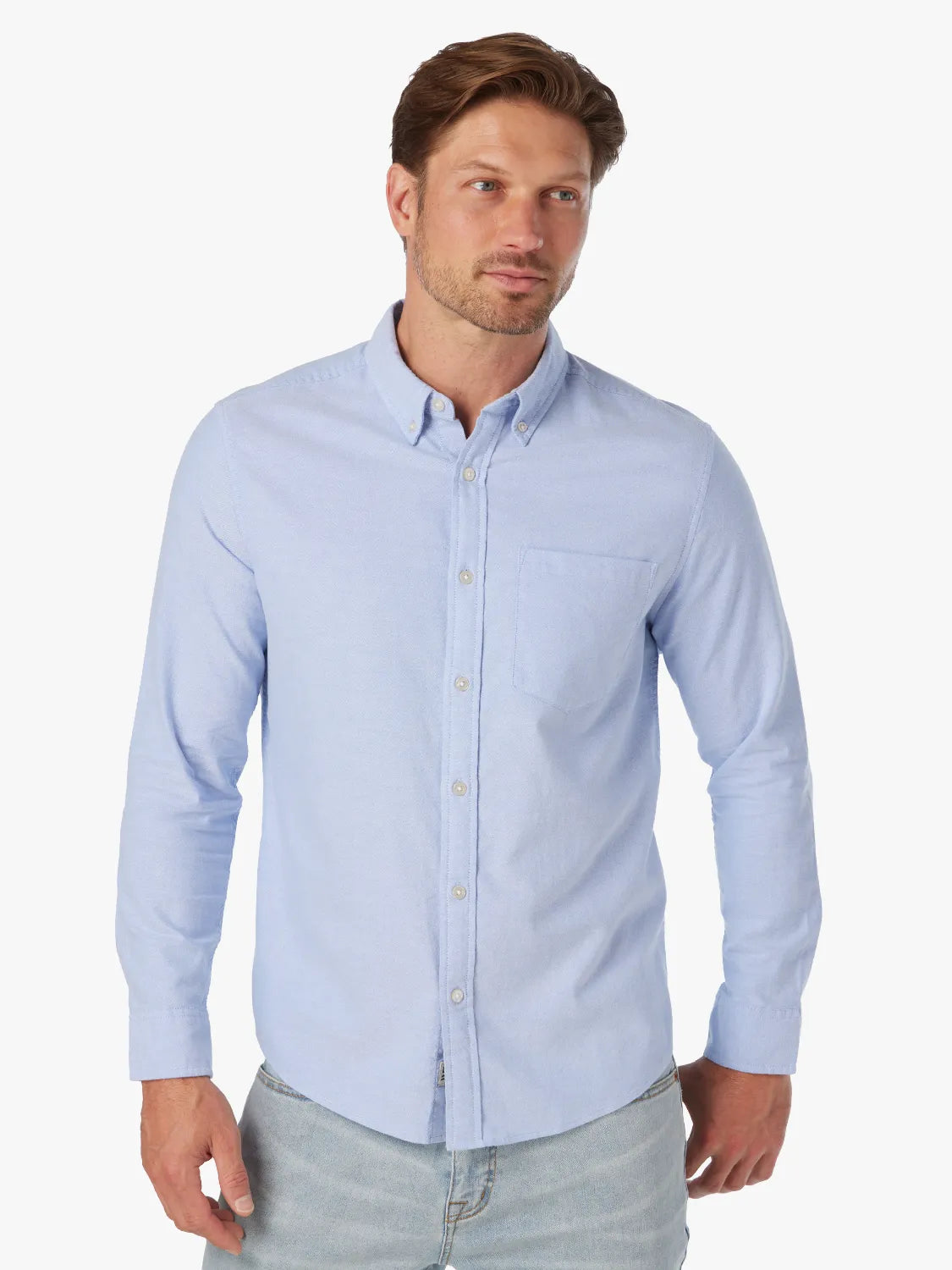Man wearing a light blue button-down oxford shirt with long sleeves and a chest pocket.