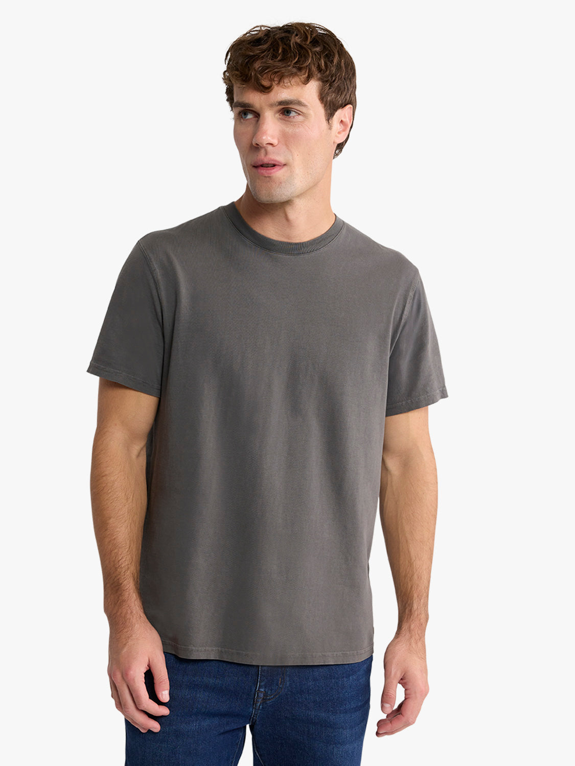 Man wearing a charcoal gray crew-neck short-sleeve t-shirt with dark jeans.