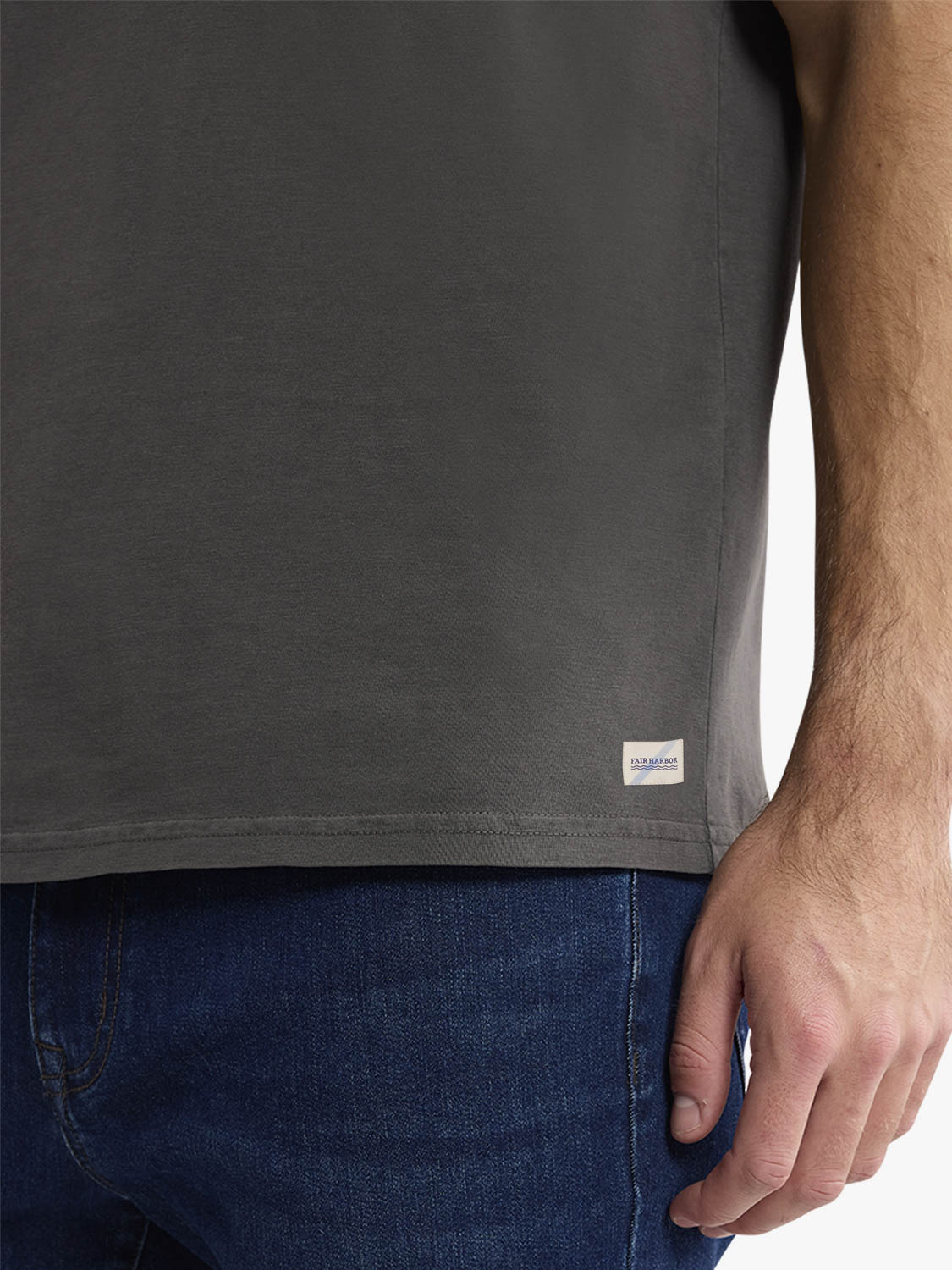 Black t-shirt on a person wearing blue denim jeans, showing side view detail.