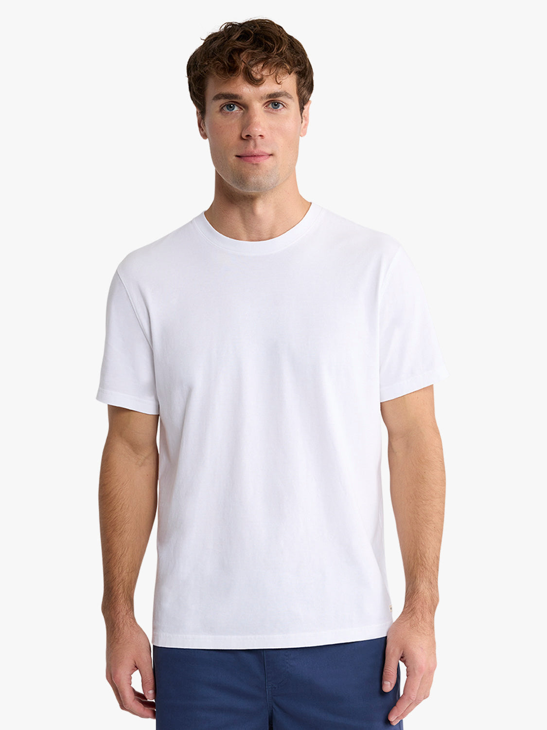 Man wearing a white crew neck t-shirt with short sleeves and dark blue shorts.