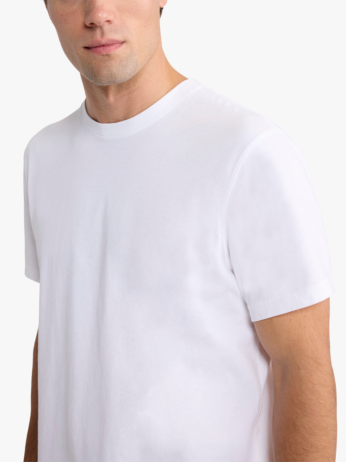 Man wearing a white short-sleeved crew neck t-shirt against a neutral background.