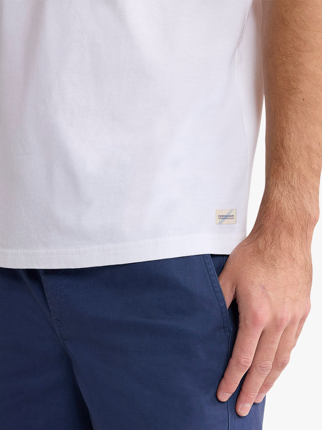 Man wearing a white short-sleeve t-shirt with a small woven label on the side seam.