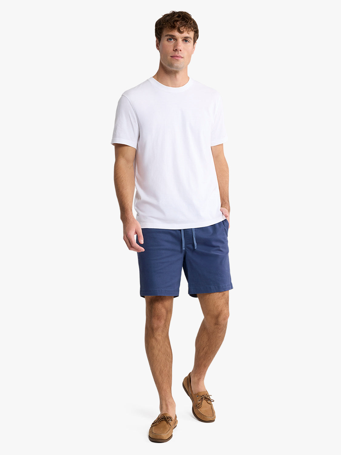 Man wearing white short-sleeve crew neck t-shirt with navy shorts and tan boat shoes.