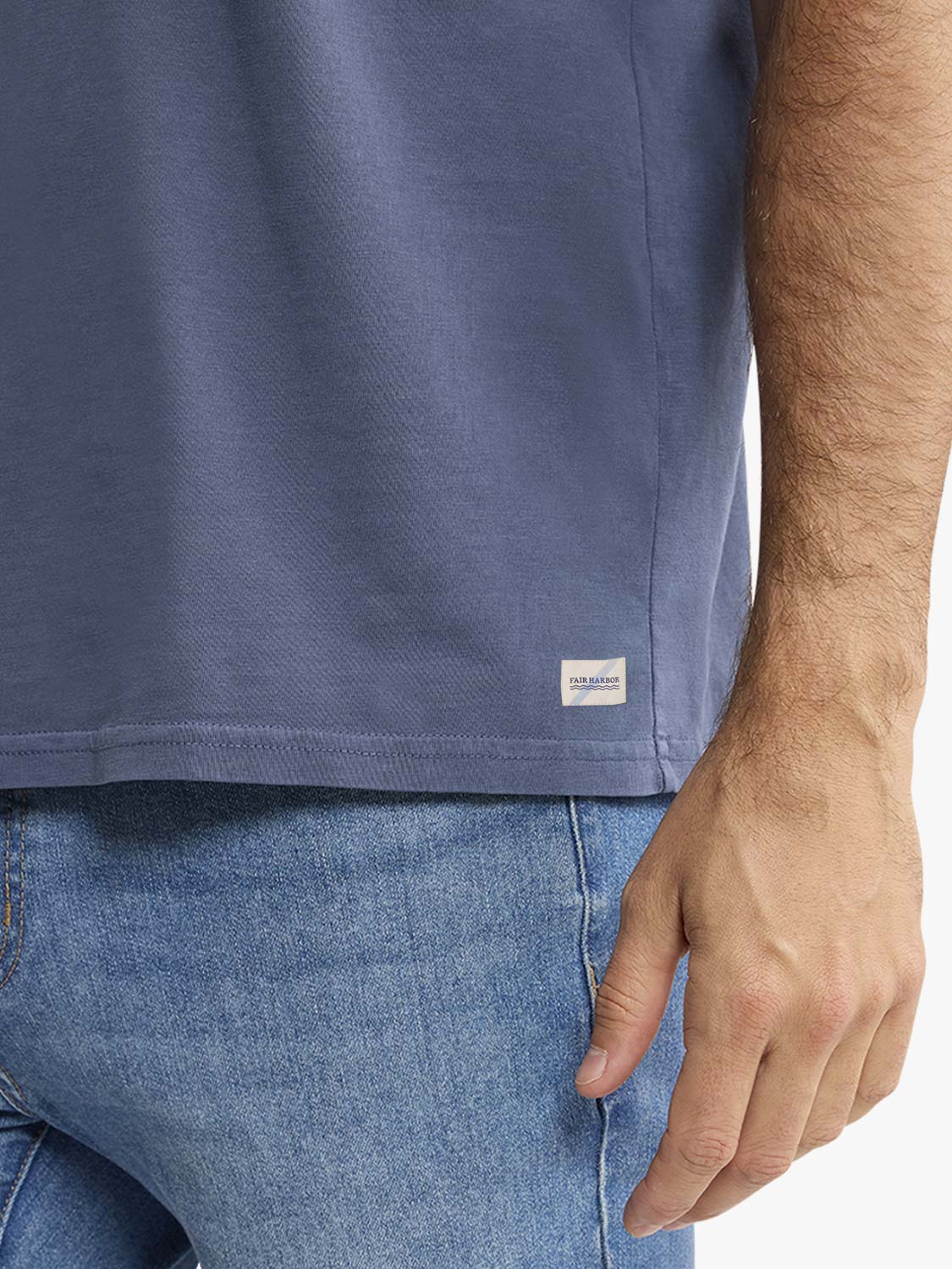 Navy crew neck t-shirt worn with blue jeans, showing side seam and small brand label detail.