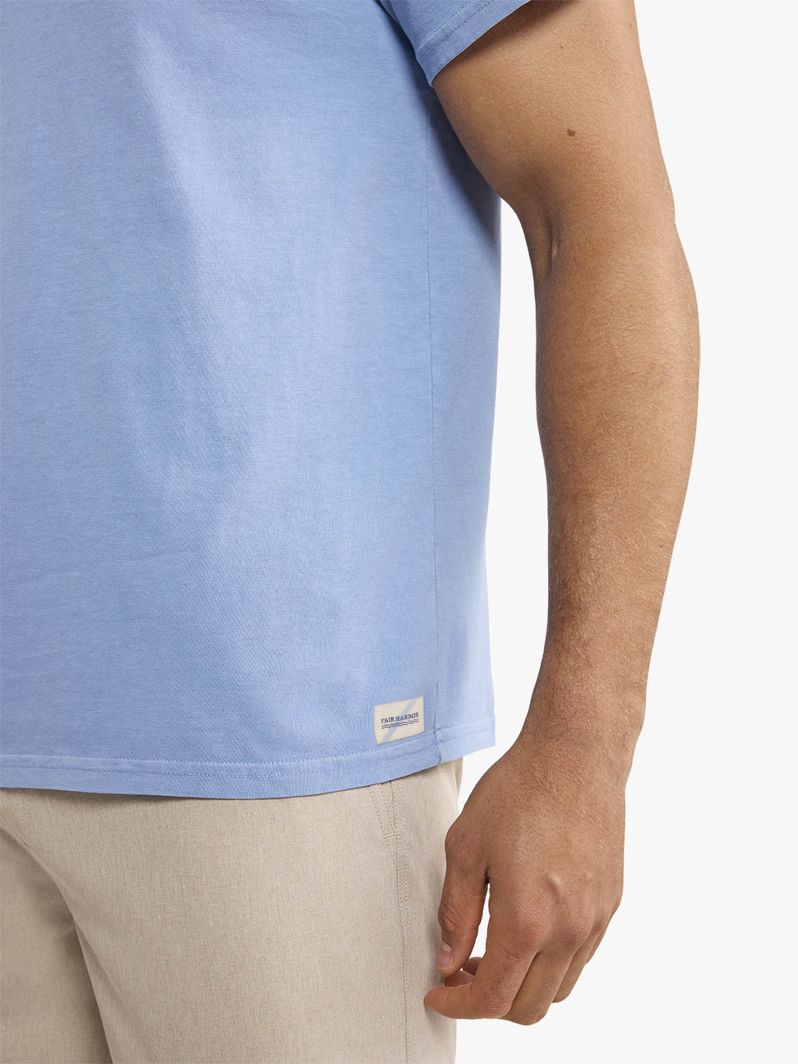 Man wearing a light blue short-sleeve t-shirt with a small label on the hem.