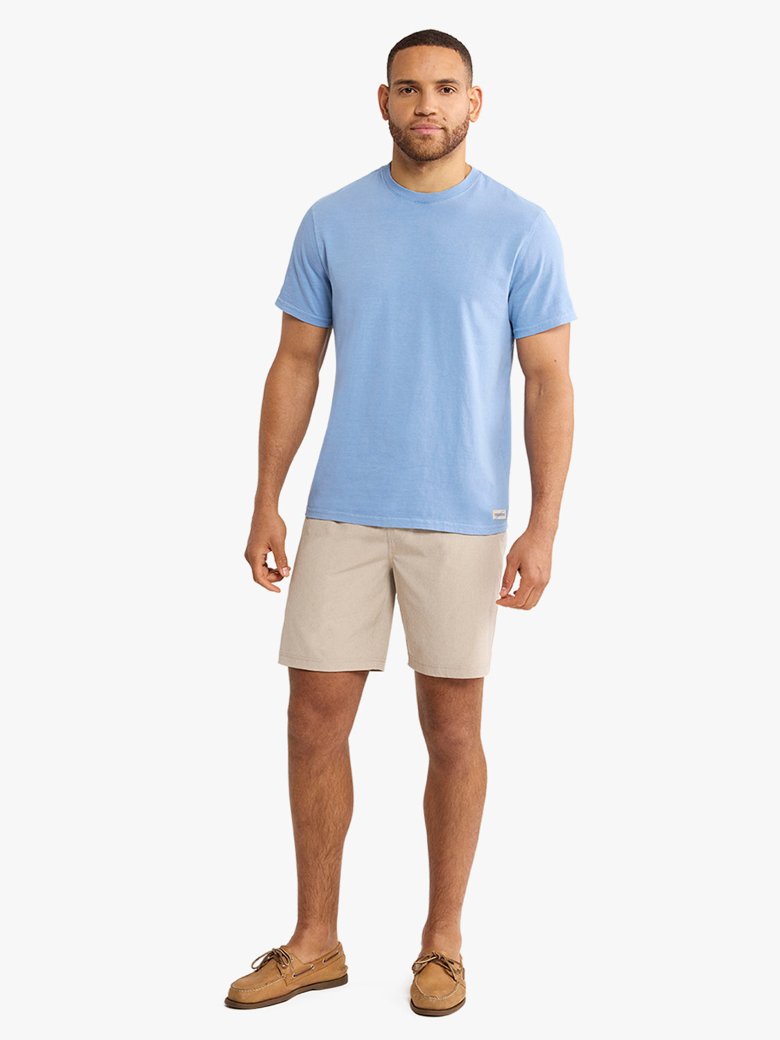 Man wearing a light blue crew neck t-shirt with beige shorts and tan boat shoes.