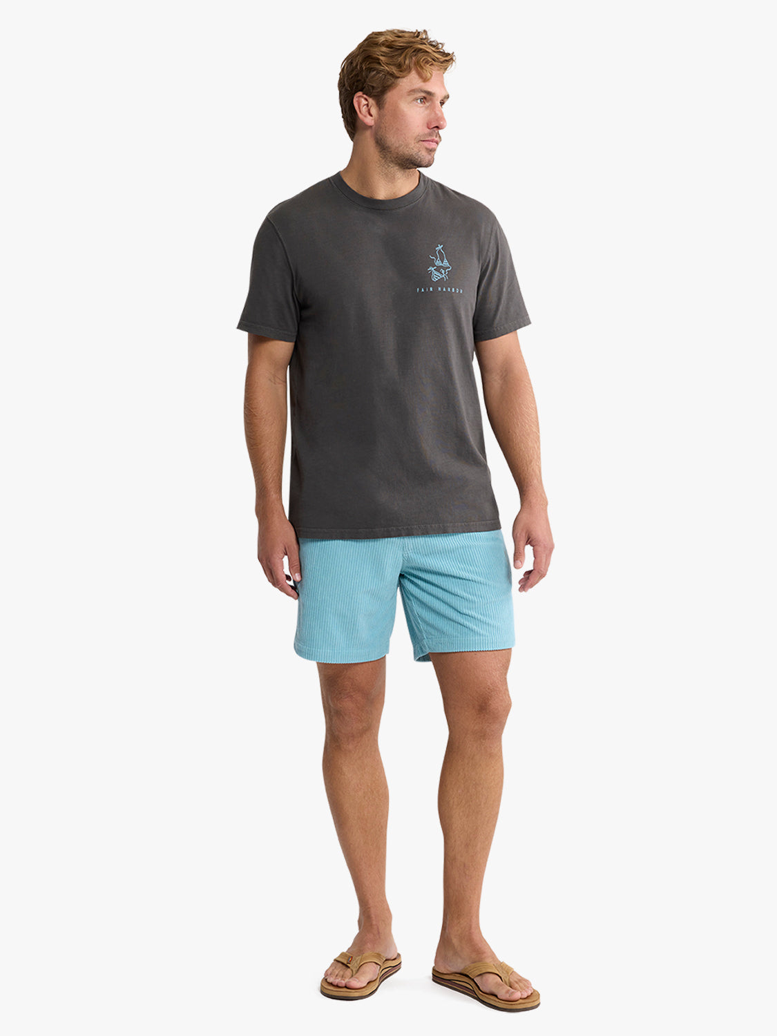 Man wearing charcoal gray graphic tee with small chest logo and light blue ribbed shorts.