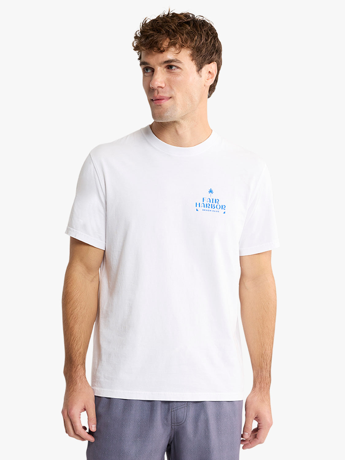 Man wearing a white short-sleeved t-shirt with blue Fair Harbor graphic print on chest.