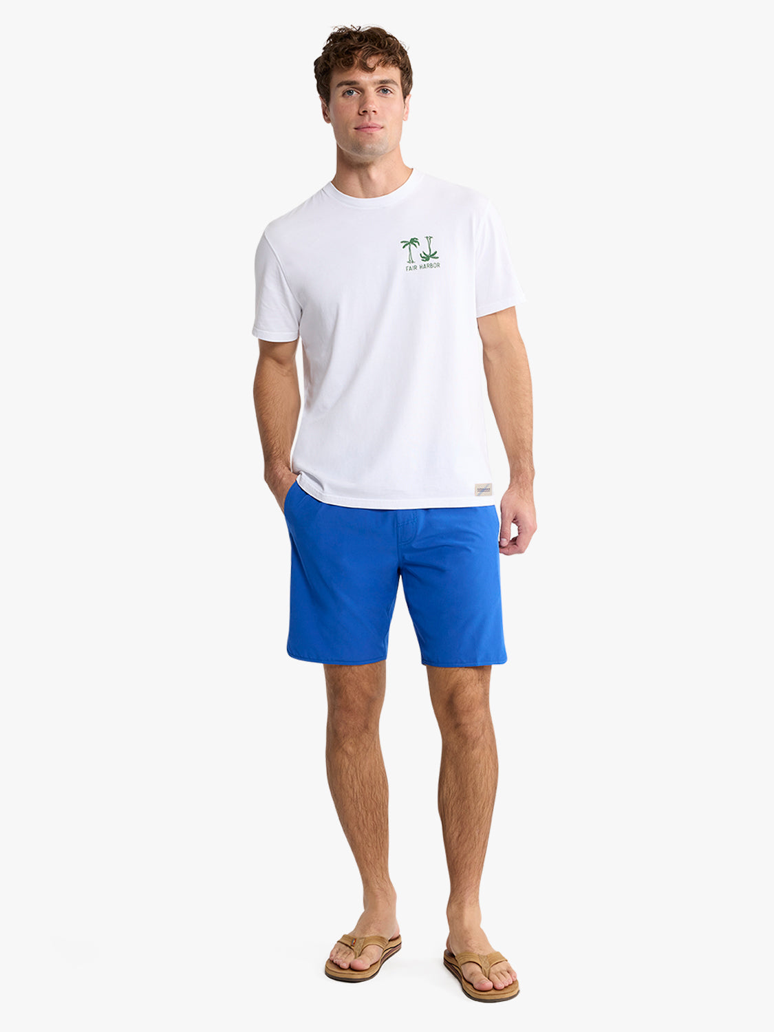 Man wearing white short-sleeve t-shirt with small palm tree graphic and blue shorts.