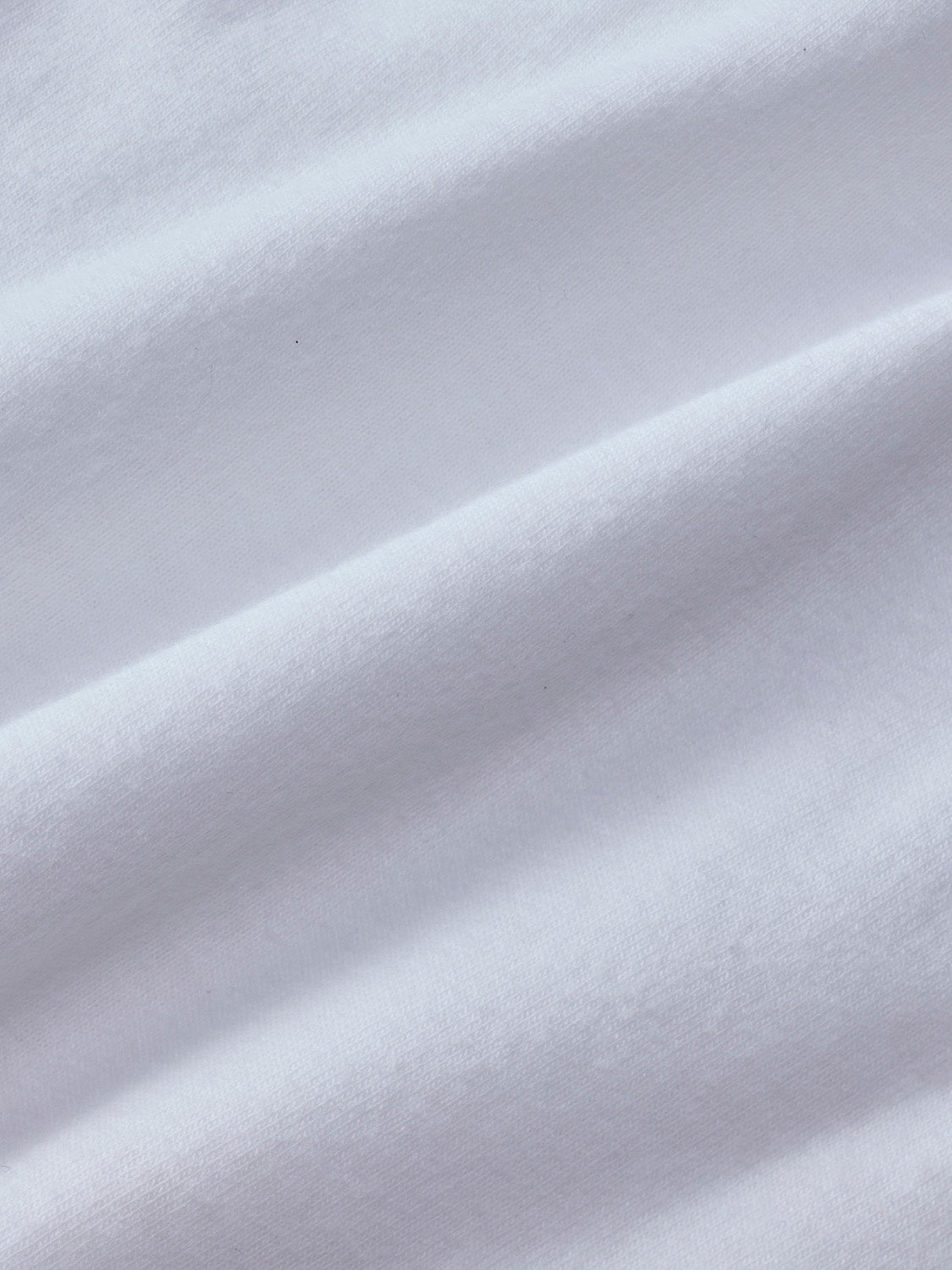 White graphic tee with checkered palm tree pattern displayed on folded fabric.