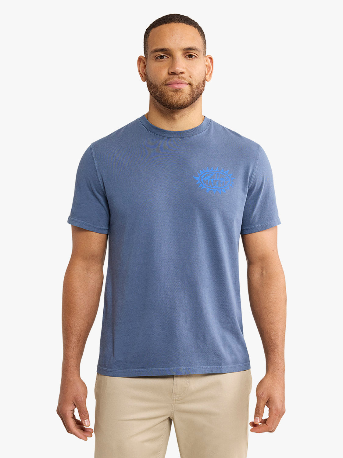 Man wearing a blue graphic tee with a blue chest design and beige pants.