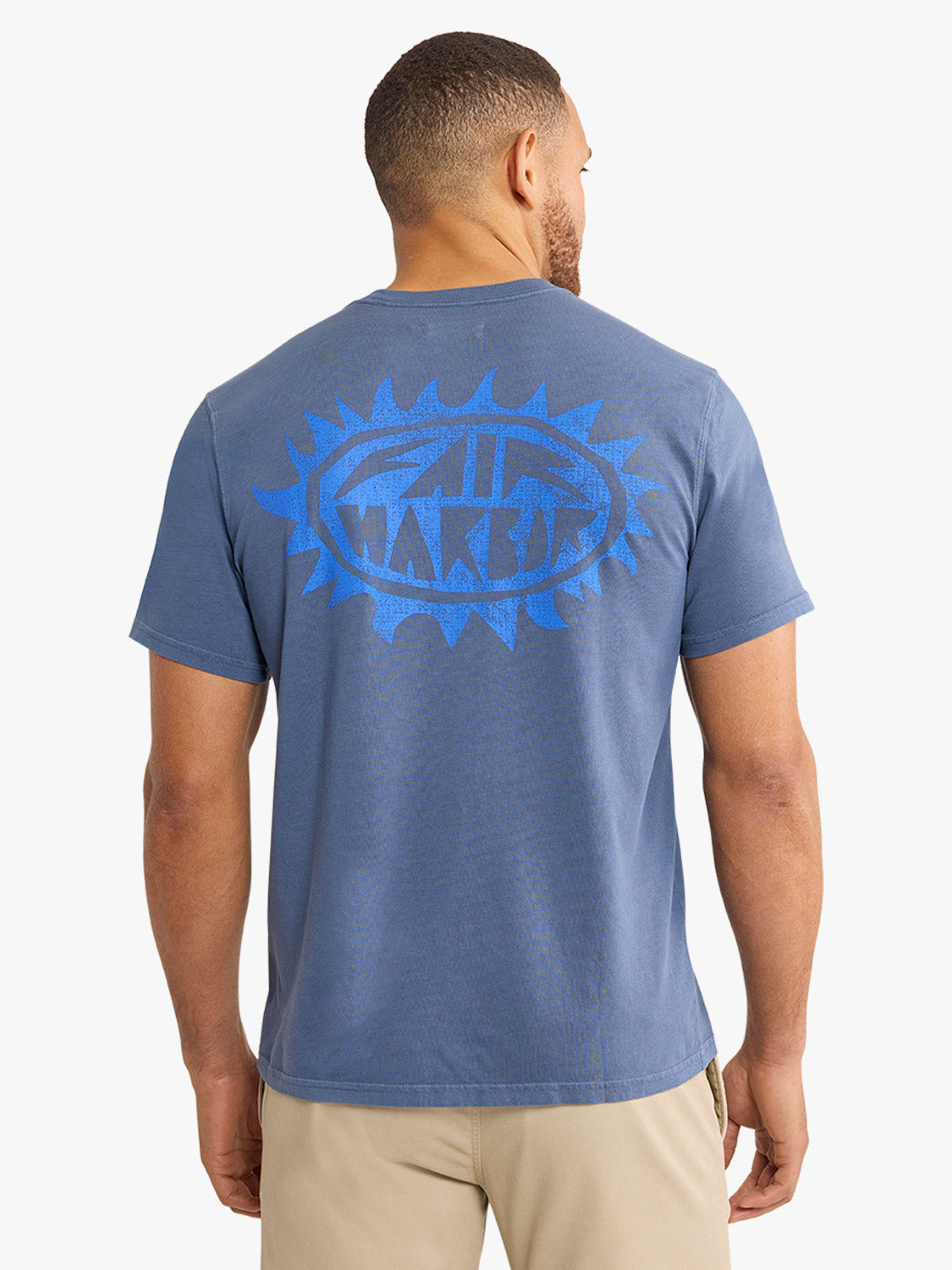 Man wearing a blue graphic tee with a retro sun design printed on the back.