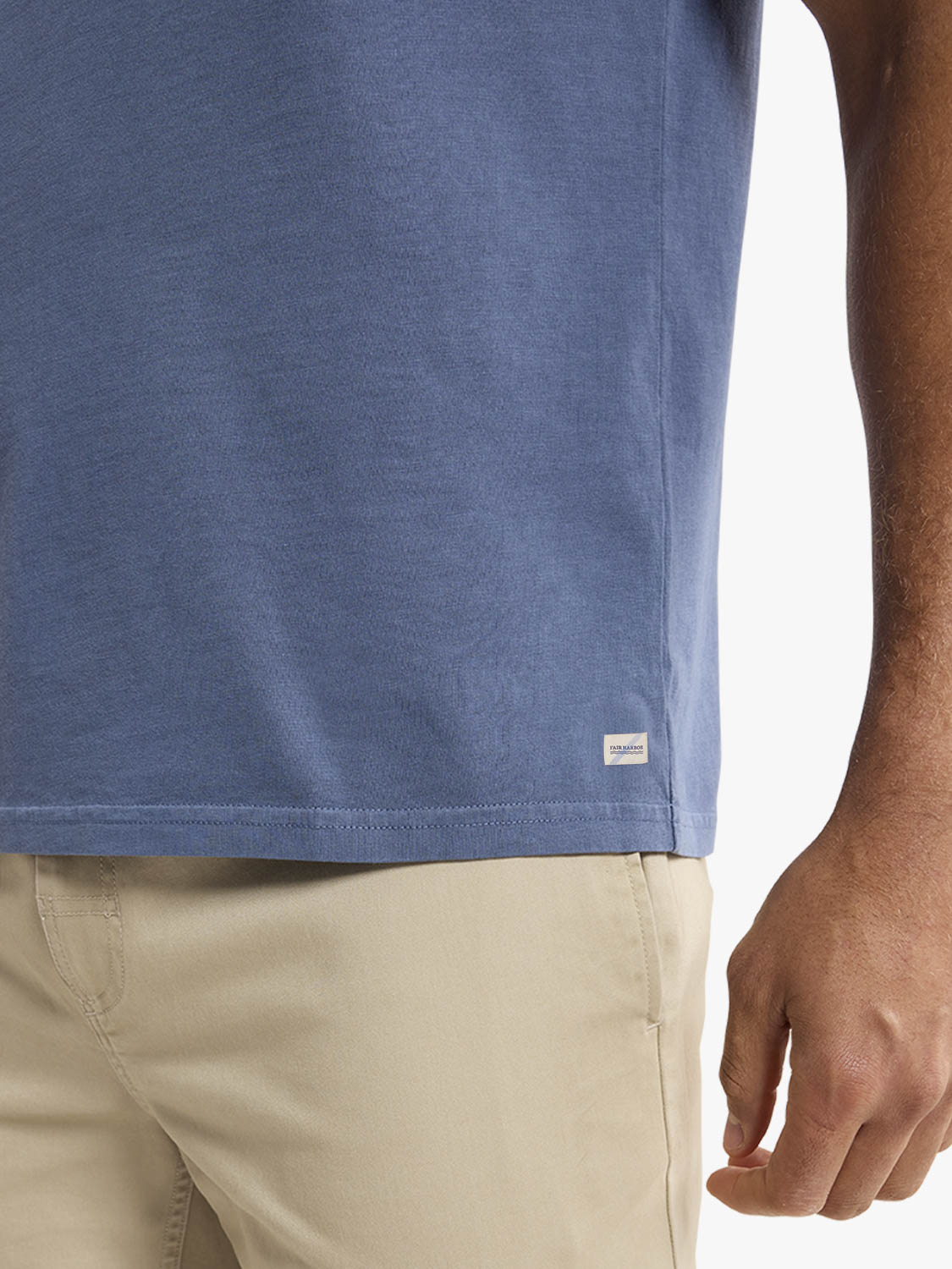 Man wearing a blue-gray graphic tee with a small rectangular label on the side.