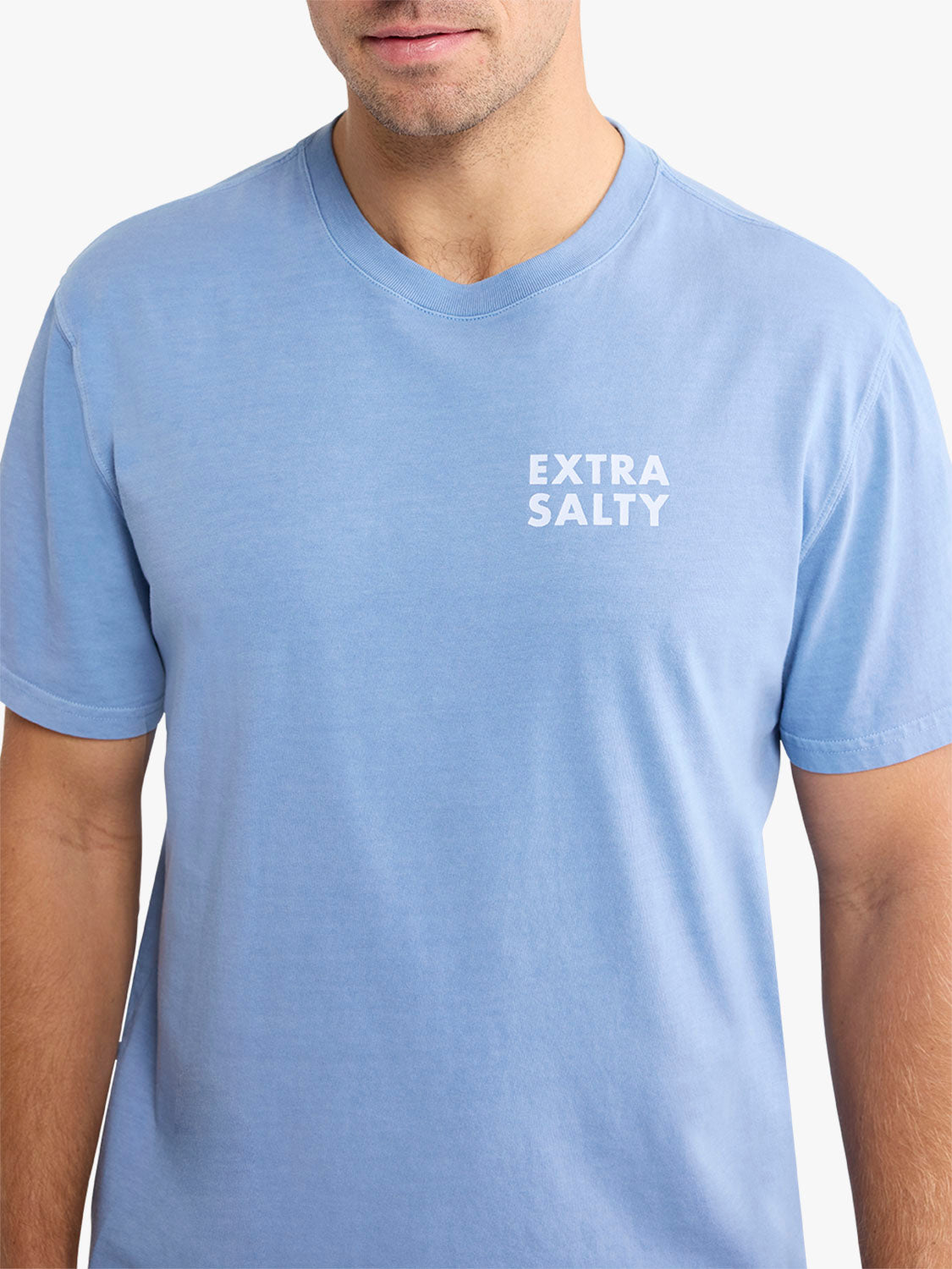 Man wearing a light blue v-neck t-shirt with white text reading extra salty on chest.
